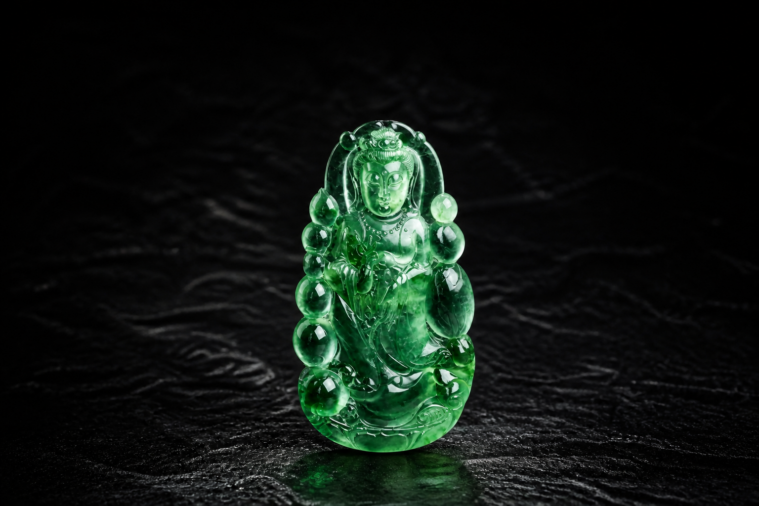 深色背景前展示的浓绿色翡翠观音雕件